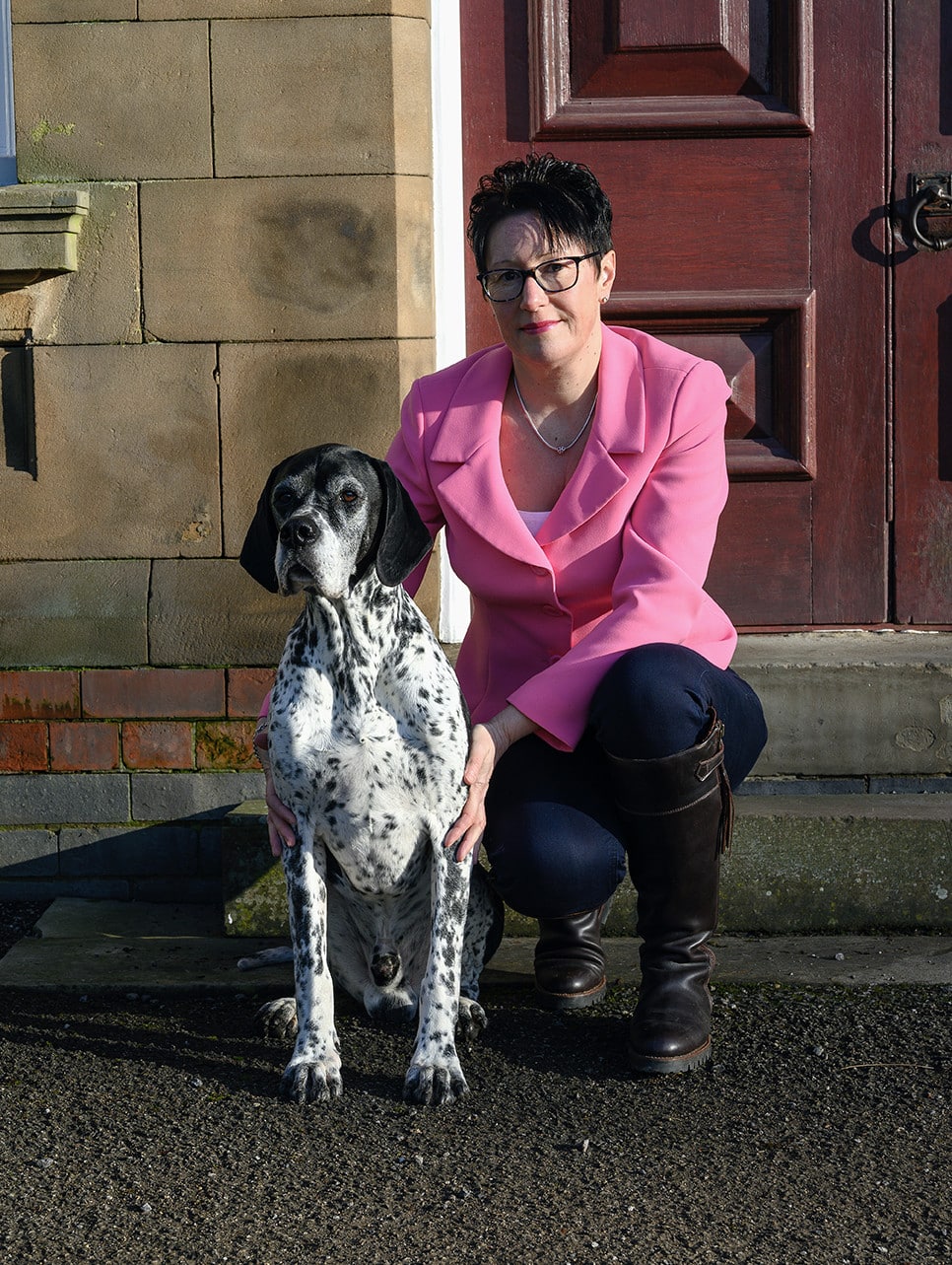 Jayne Harrison knelt next to an old dog by a doorstep